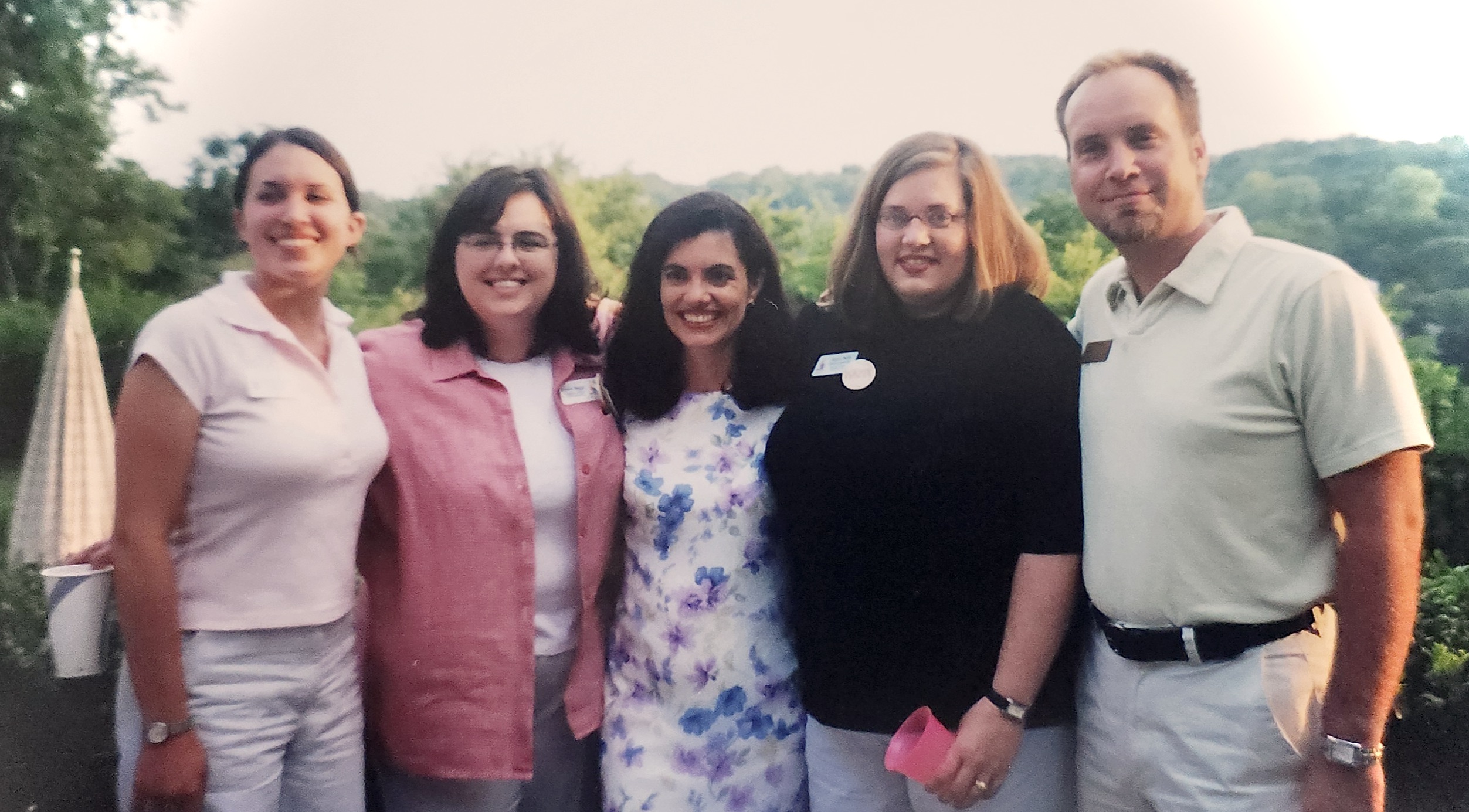 Five people pose with a treed skyline in the background