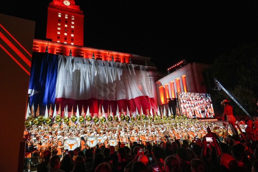 Texas Longhorn band in front of The Tower, lit up at night.
