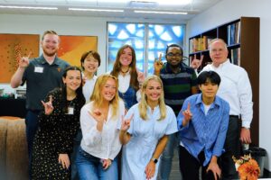 Group of students and John Dalton give the Hook 'em hand sign