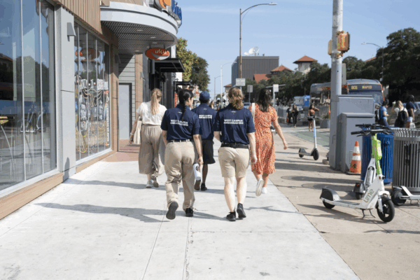 West Campus Ambassadors walk with community members along a lively stretch of Guadalupe St.
