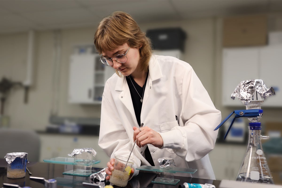Student in white lab coat with lab equipment