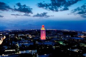 Aerial shot of the University of Texas at Austin Tower lit up orange at night with a 