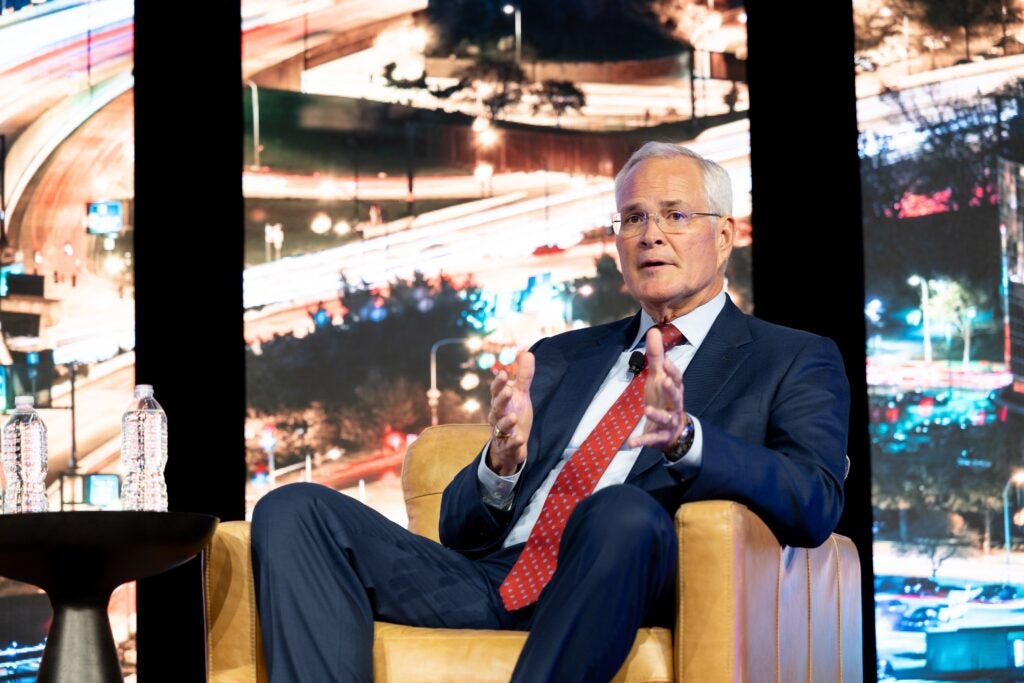 Darren Woods sits, speaking on stage