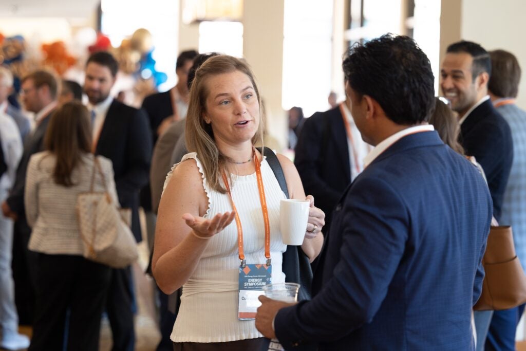 Woman with a cup of coffee stands talking to a man
