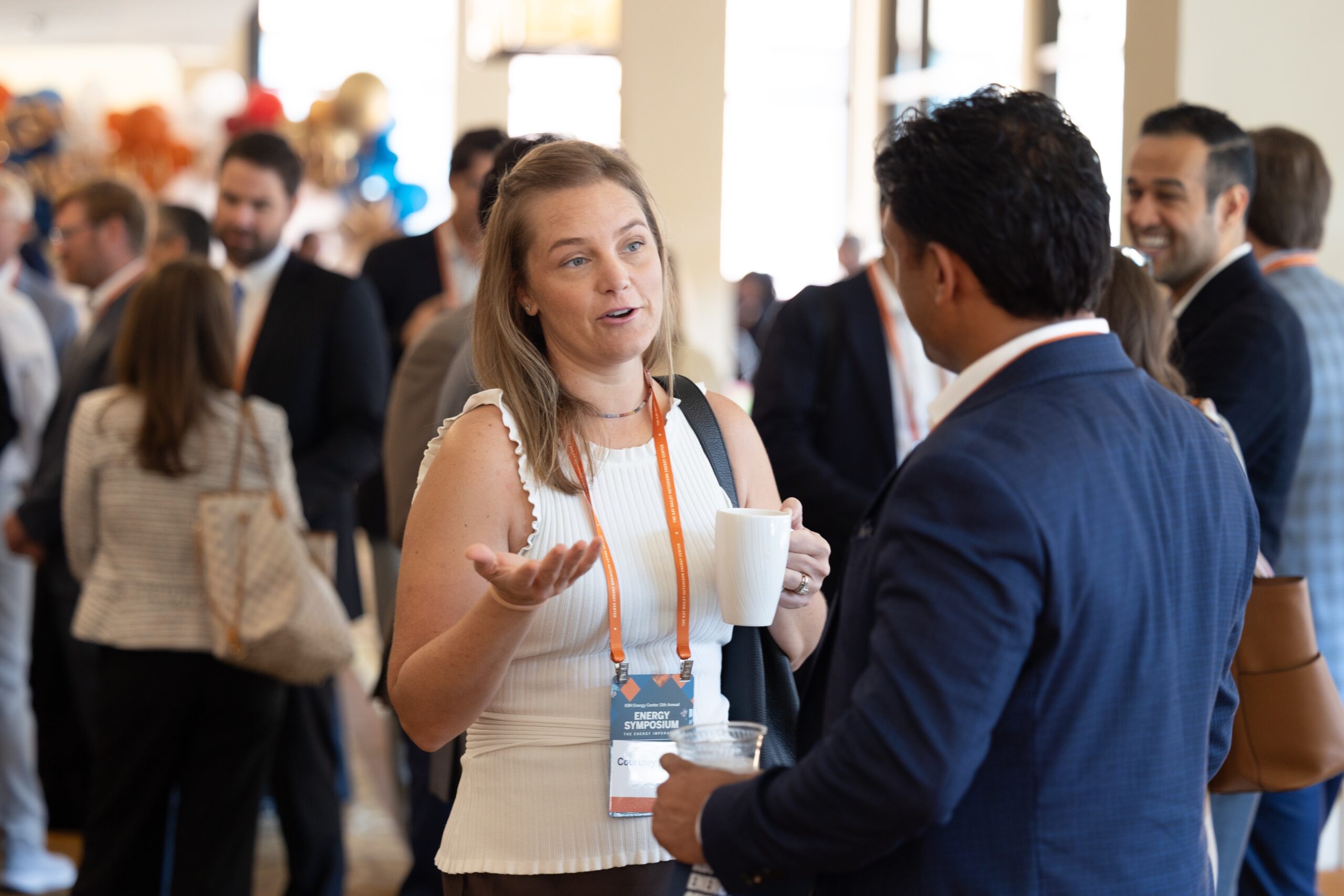 Woman with a cup of coffee stands talking to a man