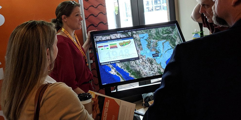 Woman stands beside screen visualizing historical well data