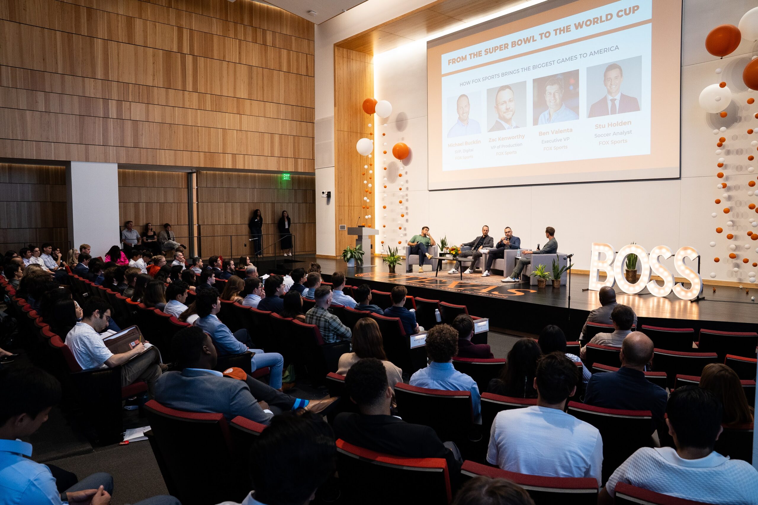 An audience watches a panel discussion in an auditorium.