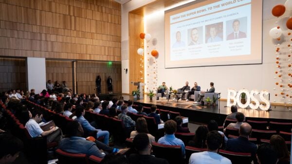 An audience watches a panel discussion in an auditorium.