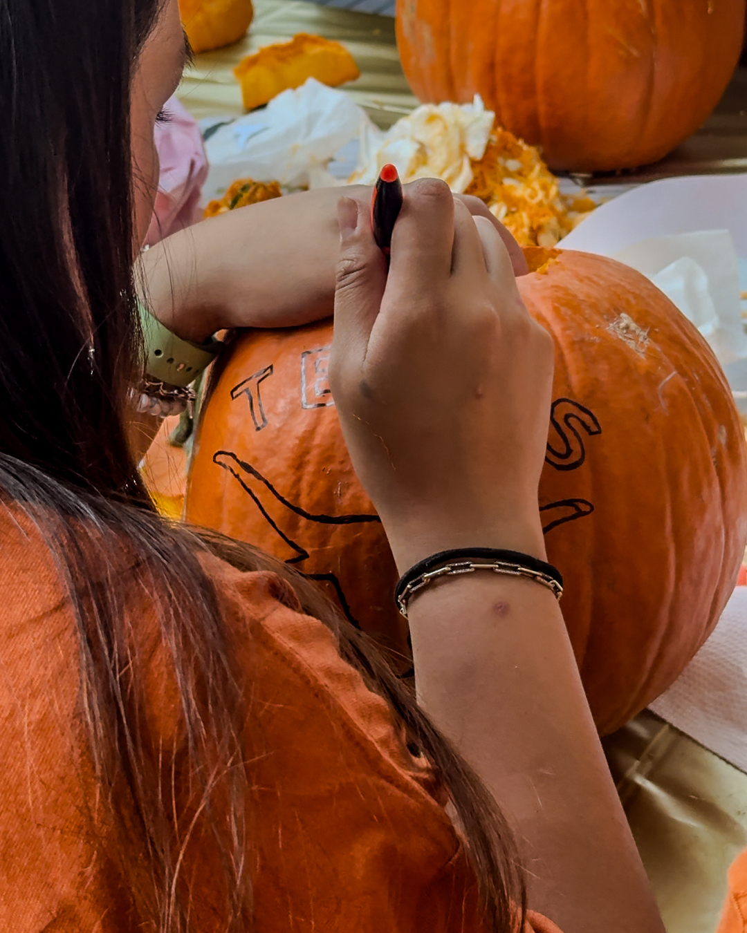 A U.T. Austin student carving a Longhorn themed jack-o’-lantern.