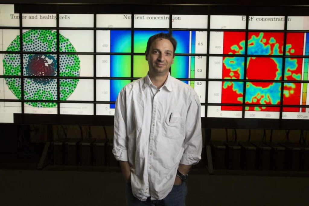 Man stands in front of three screens with graphics