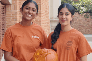 Two students holding a carved pumpkin.