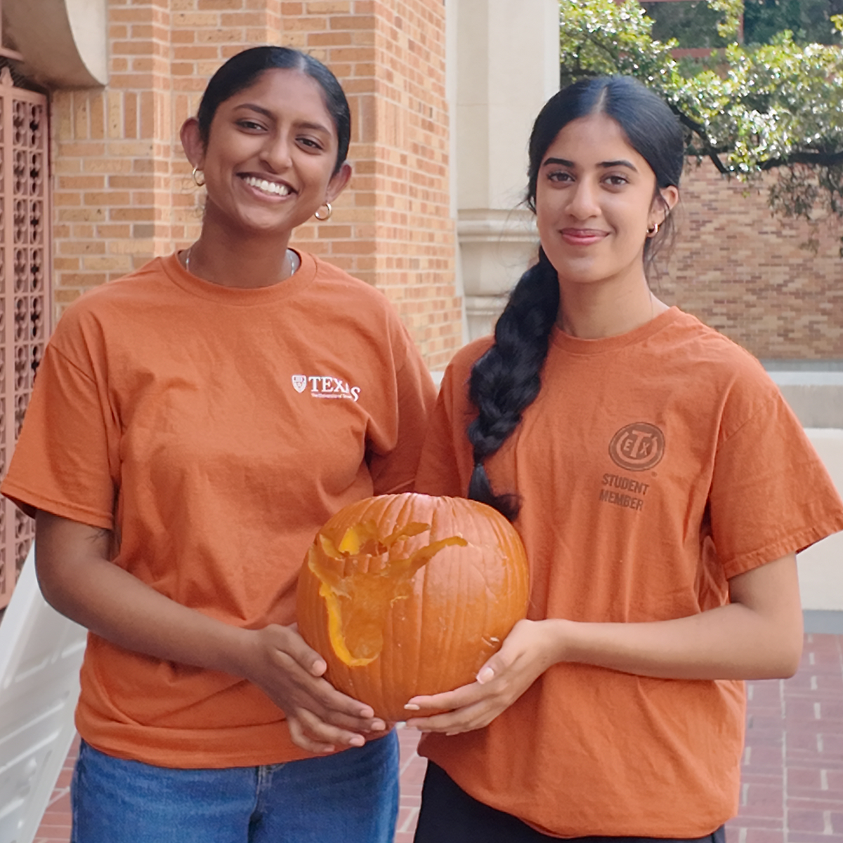 Two students holding a carved pumpkin.