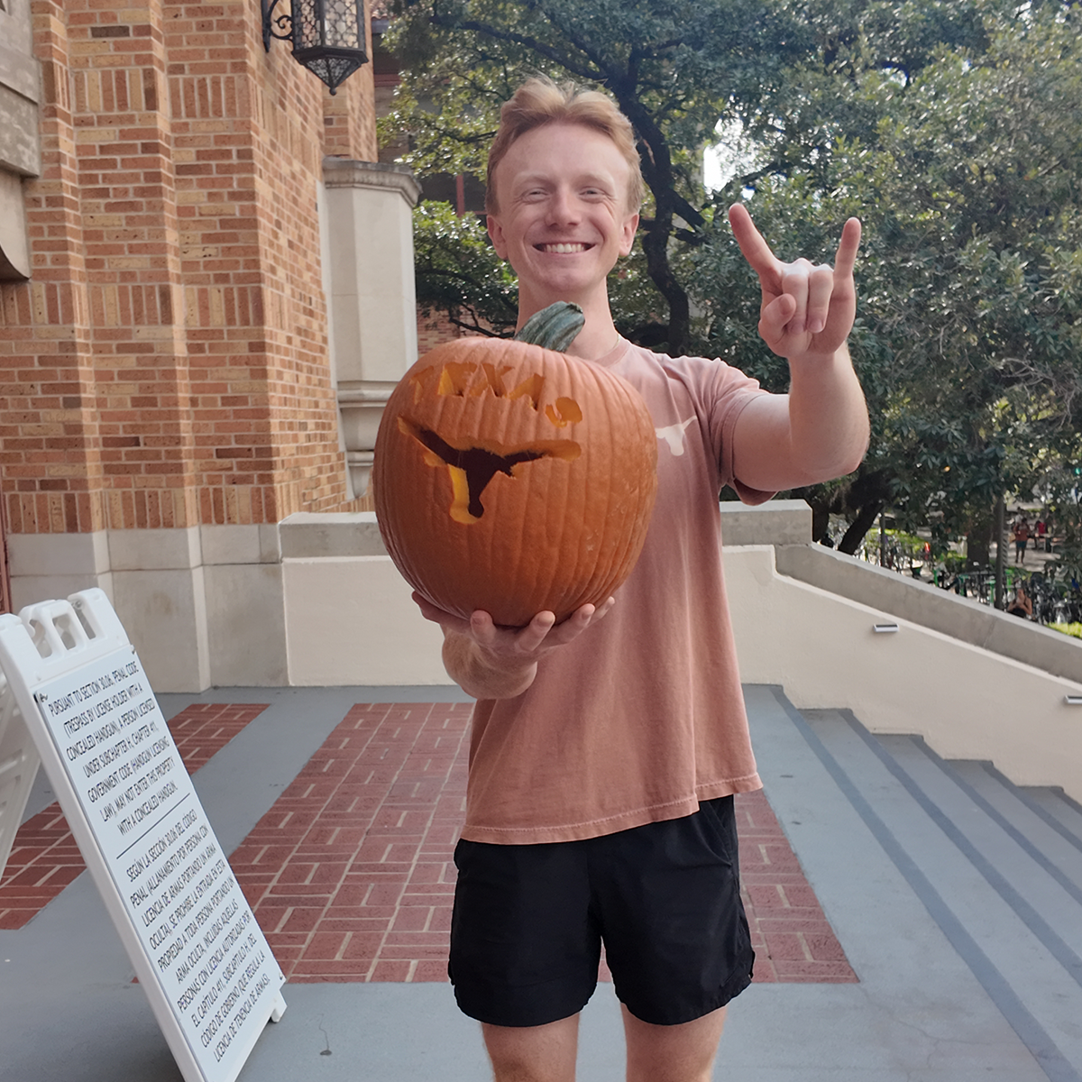 A student holding a carved pumpkin.