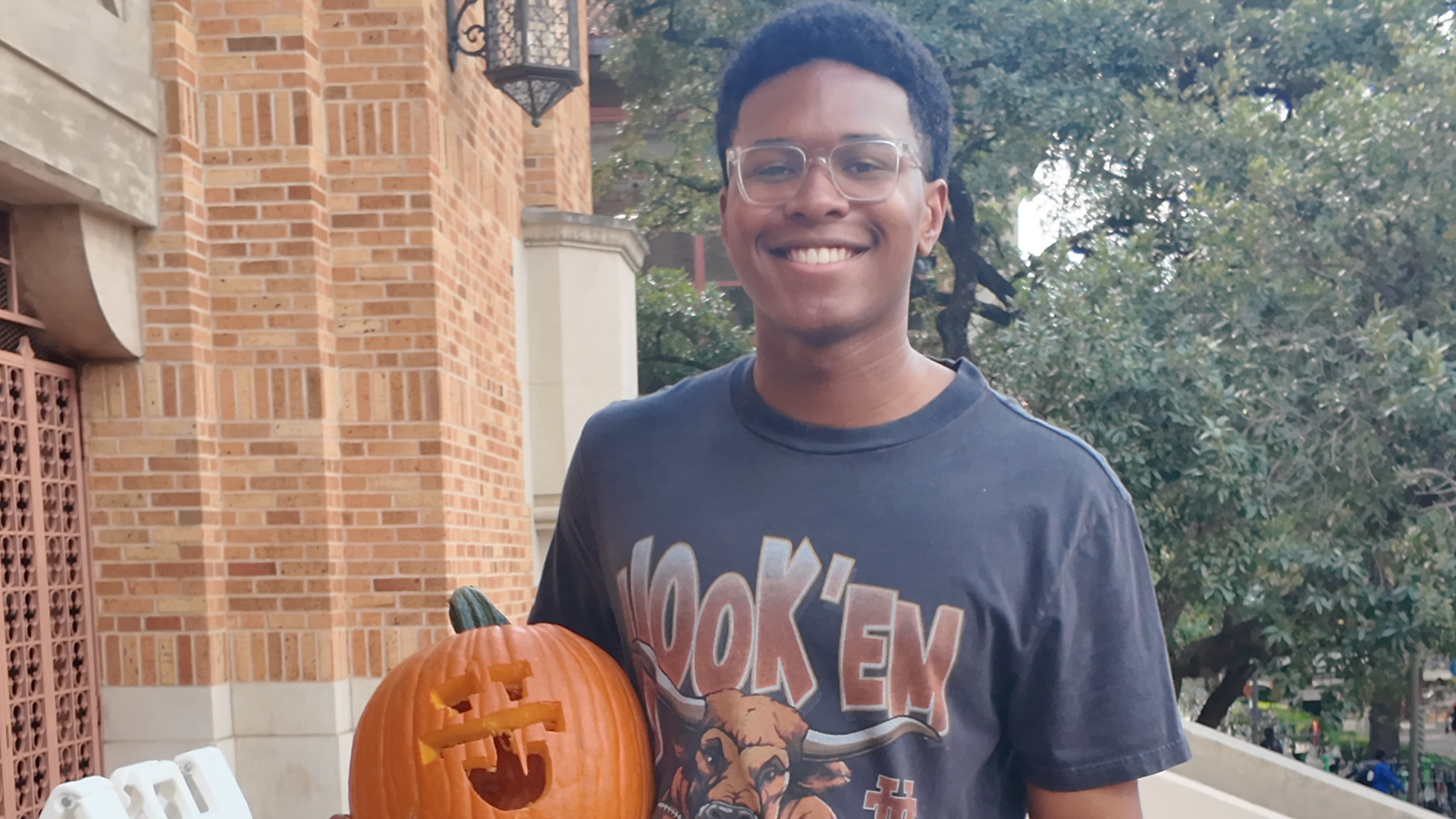 A student holding a carved pumpkin.