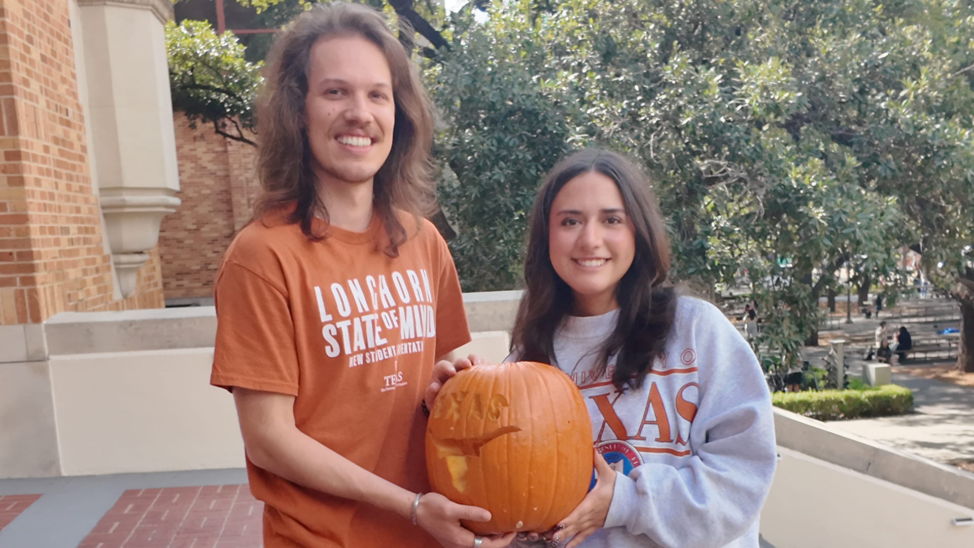 Two students holding a carved pumpkin.