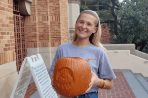 A student holding a carved pumpkin.