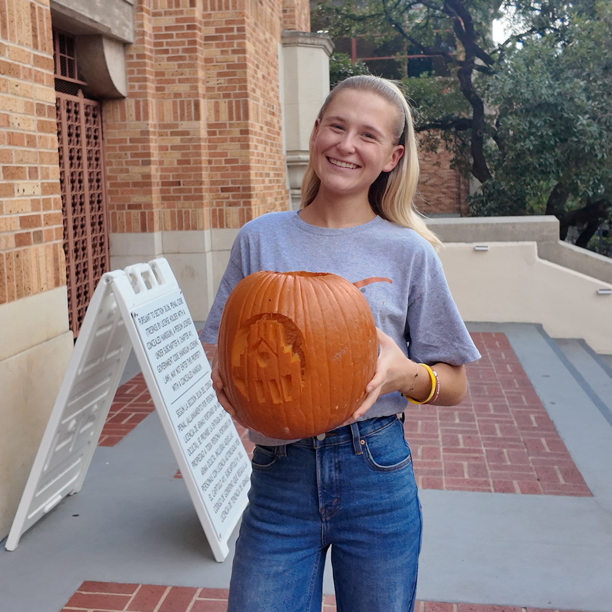 A student holding a carved pumpkin.