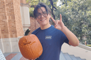 A student holding a carved pumpkin.