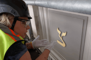 A decorative artisan examines gold leafing on a symbol on the University of Texas Tower