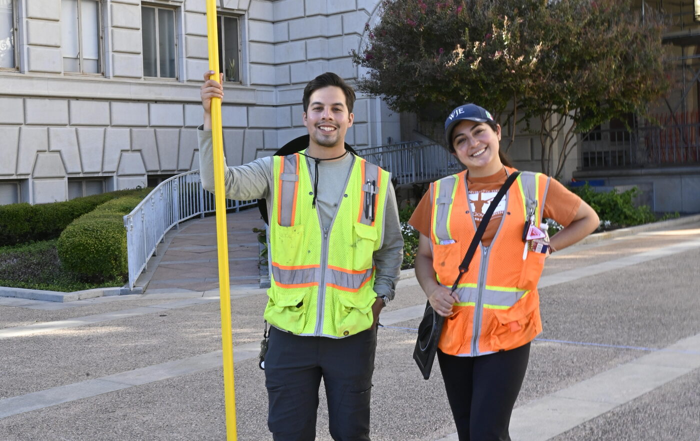 Young man and young woman in construction garb smiling