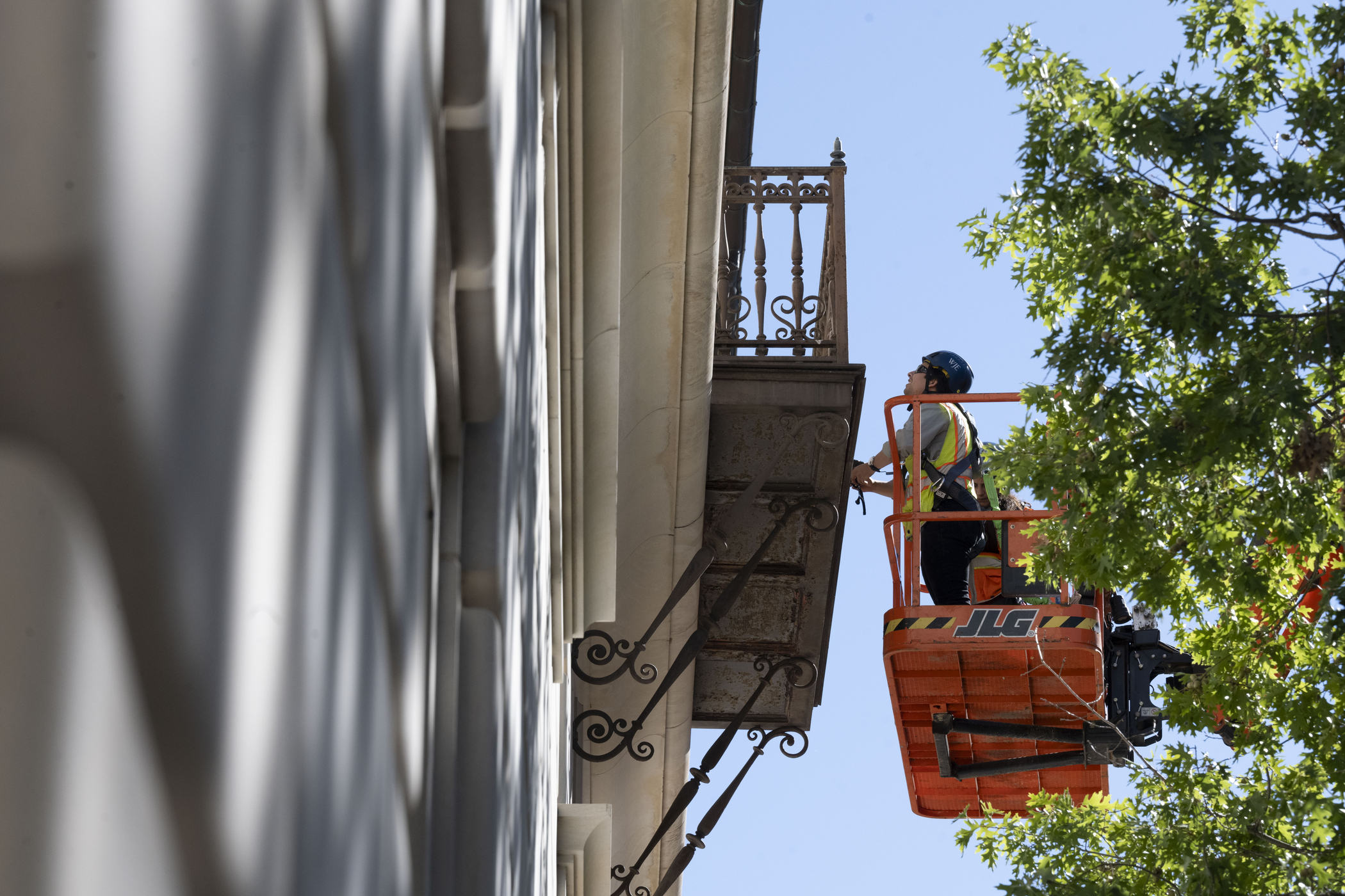 restoration worker in cherry picker examines balcony
