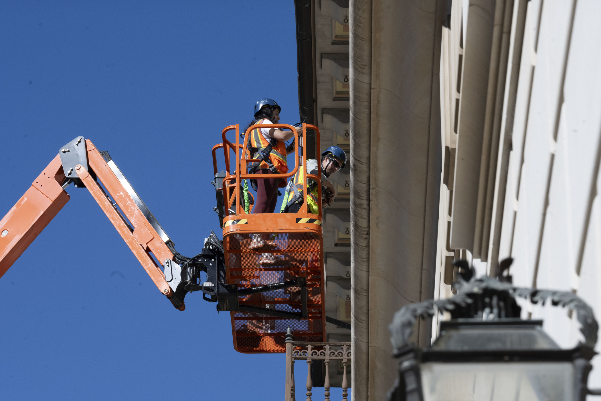 workers in cherrypicker examine balcony