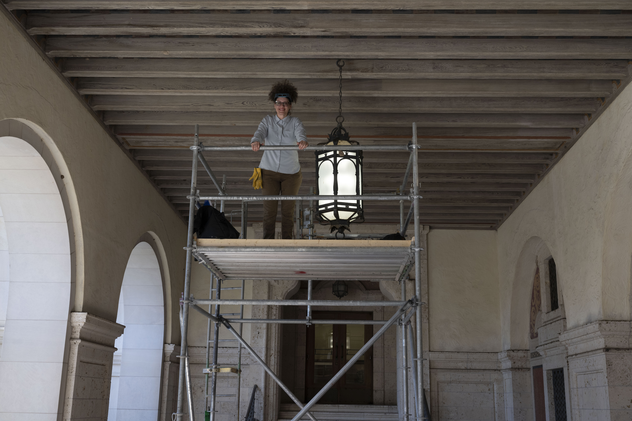 Woman on scaffold examines lantern on loggia