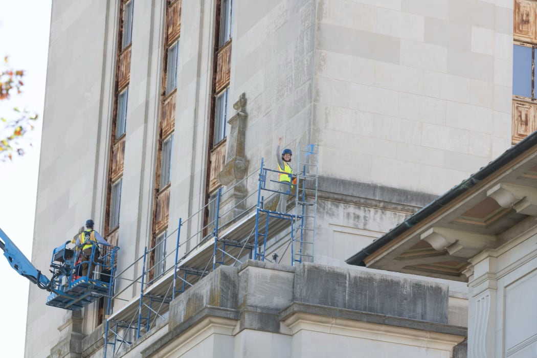 Woman on scaffold flashes hook'em sign