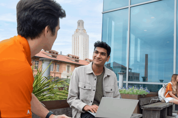 Students talking on a balcony overlooking the University of Texas at Austin Tower.