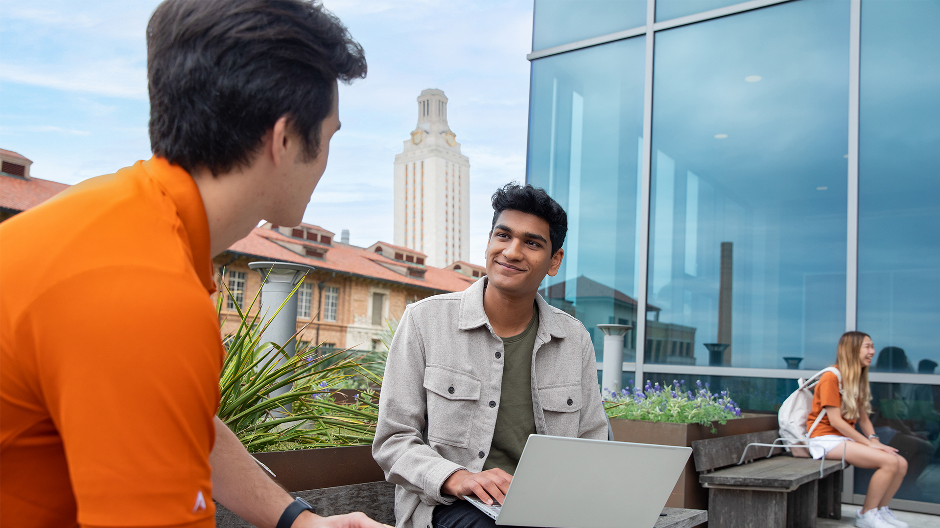 Students talking on a balcony overlooking the University of Texas at Austin Tower.