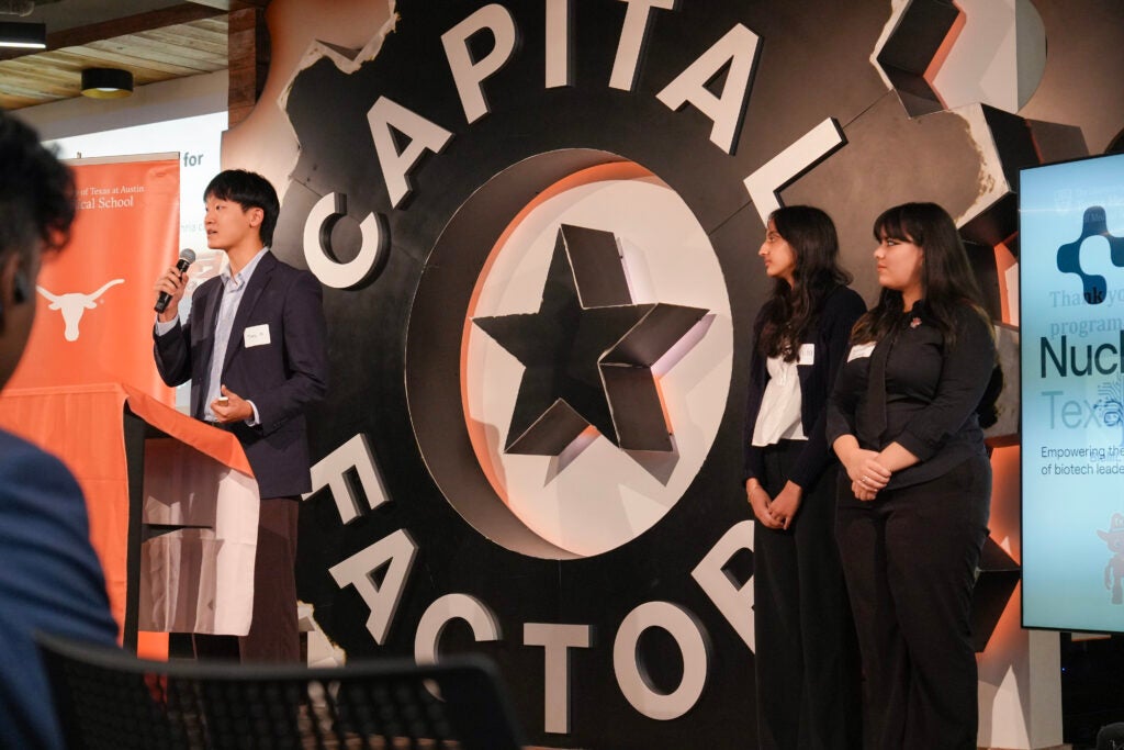 Three people stand in front of Capital Factory sign.