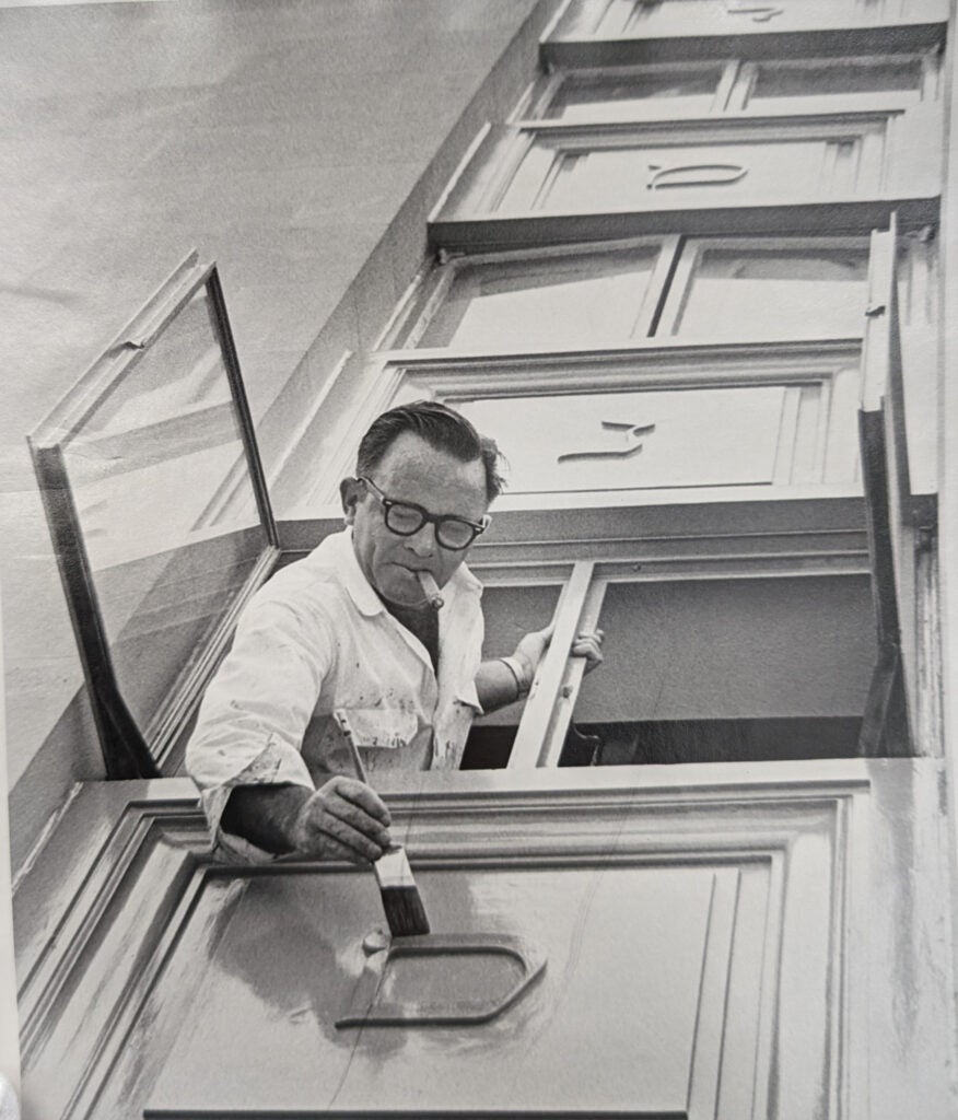 man painting letters in difficult letters on the side of the Tower