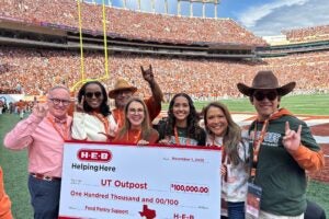 A group of people standing on a football field holding a large check.