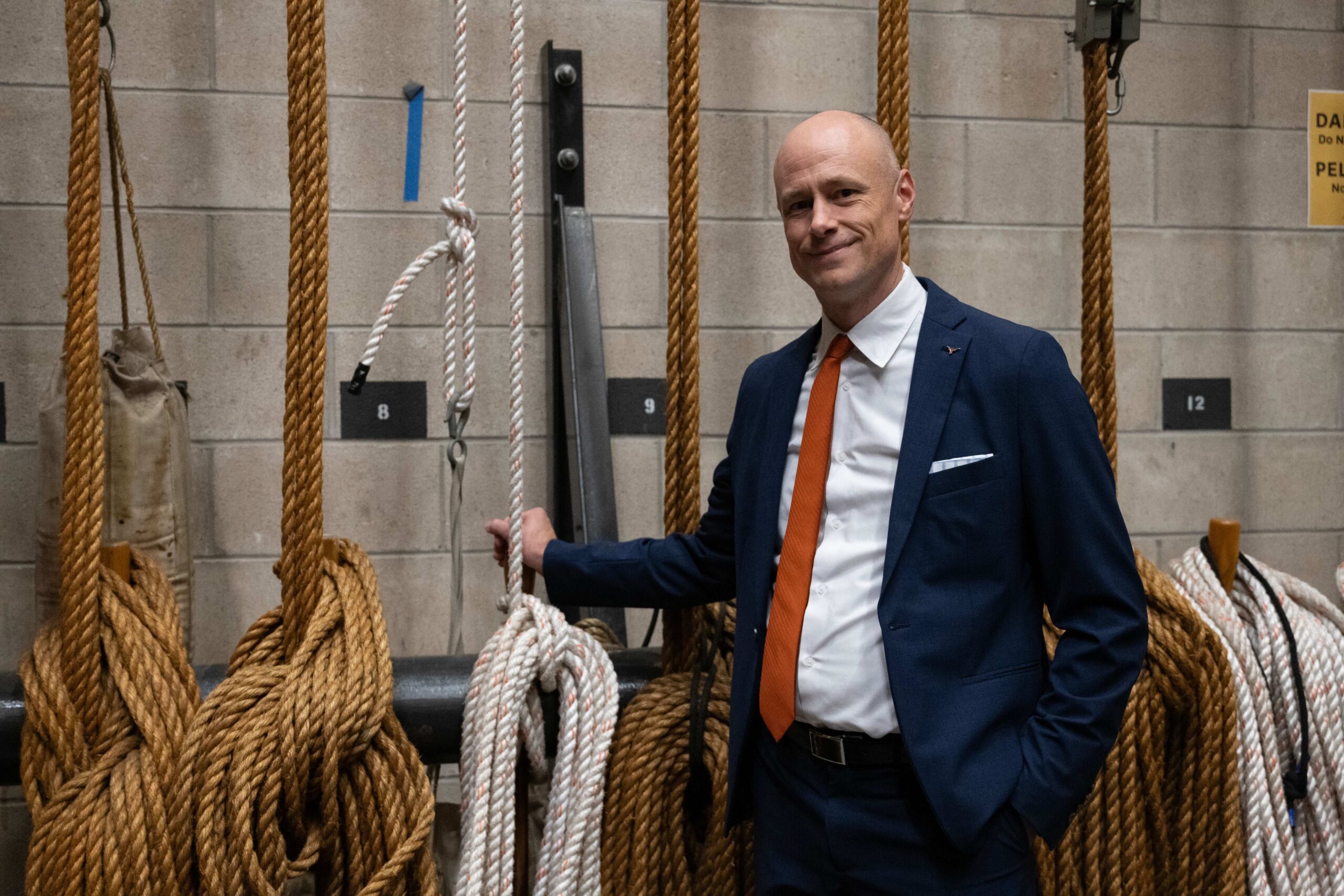 A man in a suit poses backstage in a theater.