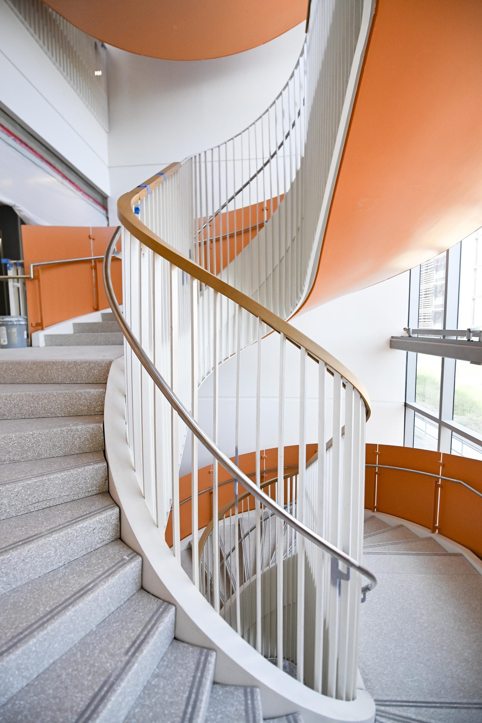 Twisting grey staircase with orange underside and open windows