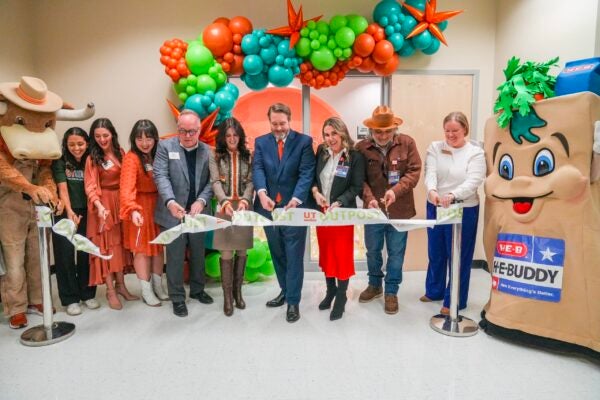 Several people stand together cutting a ribbon