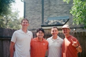 Four young men in Longhorn polos stand in backyard.