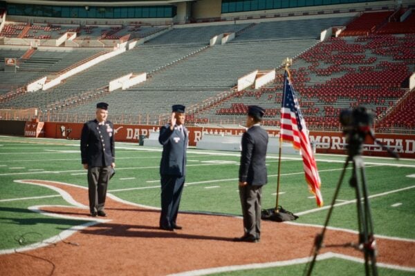 Three men in uniform next to U.S. flag at DKR Stadium