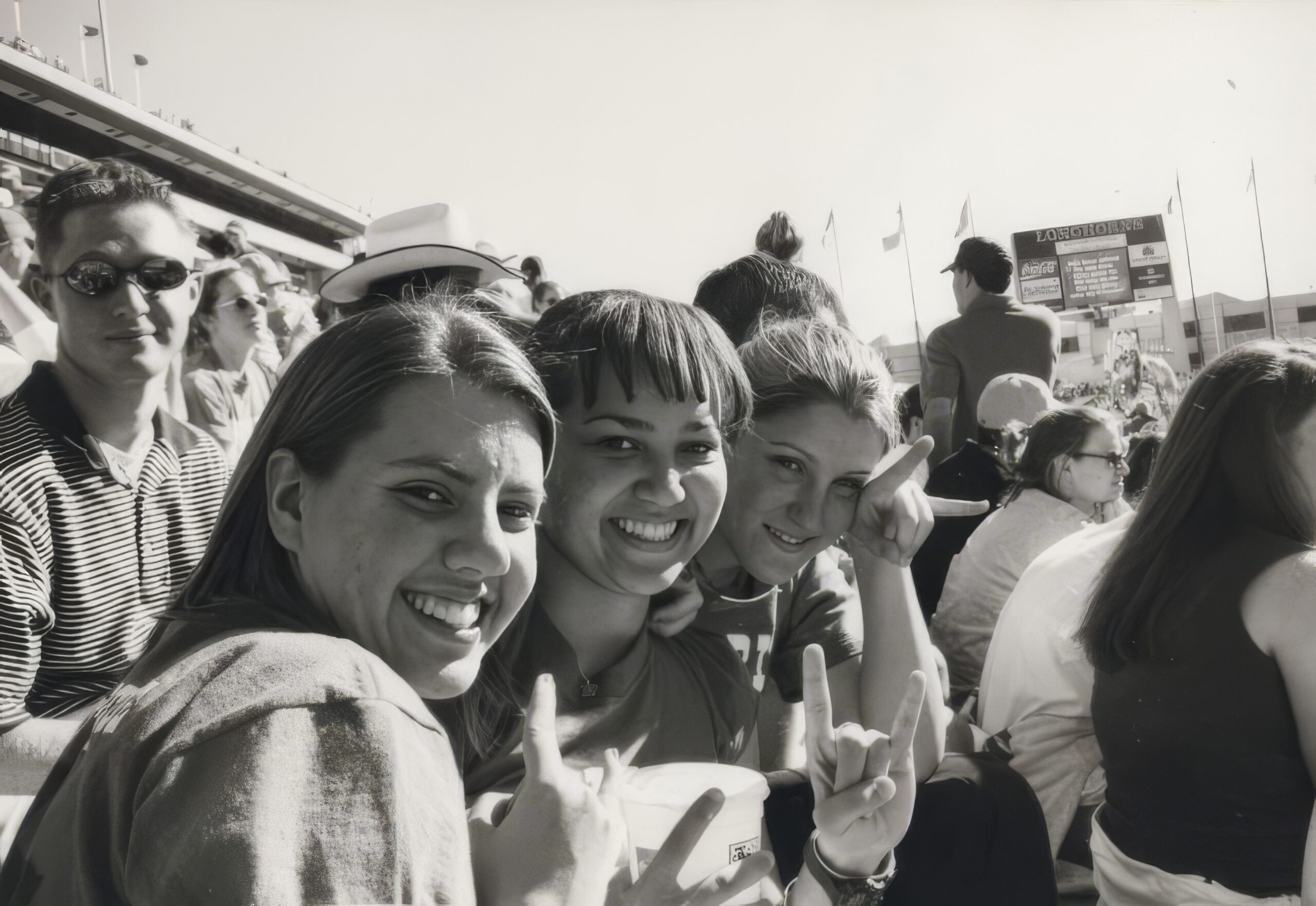 A black and white photo of students smiling at a football game.