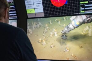 Video screen shows robot arm on ocean floor
