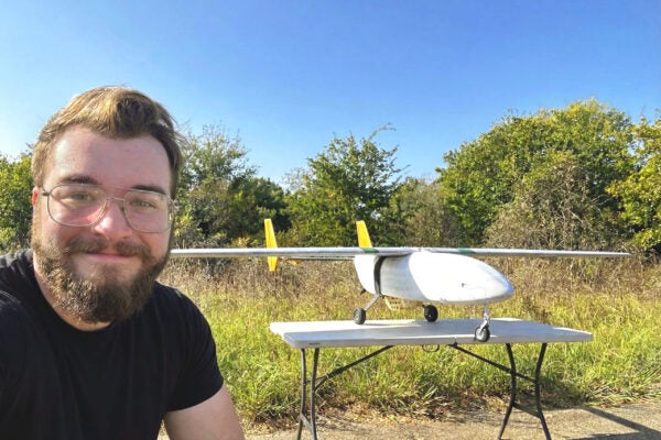 a student taking a selfie with a small aircraft sitting on a table