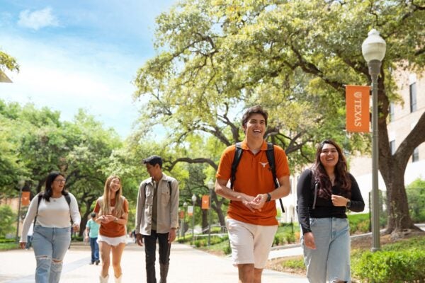 image of five students walking down speedway wearing backpacks
