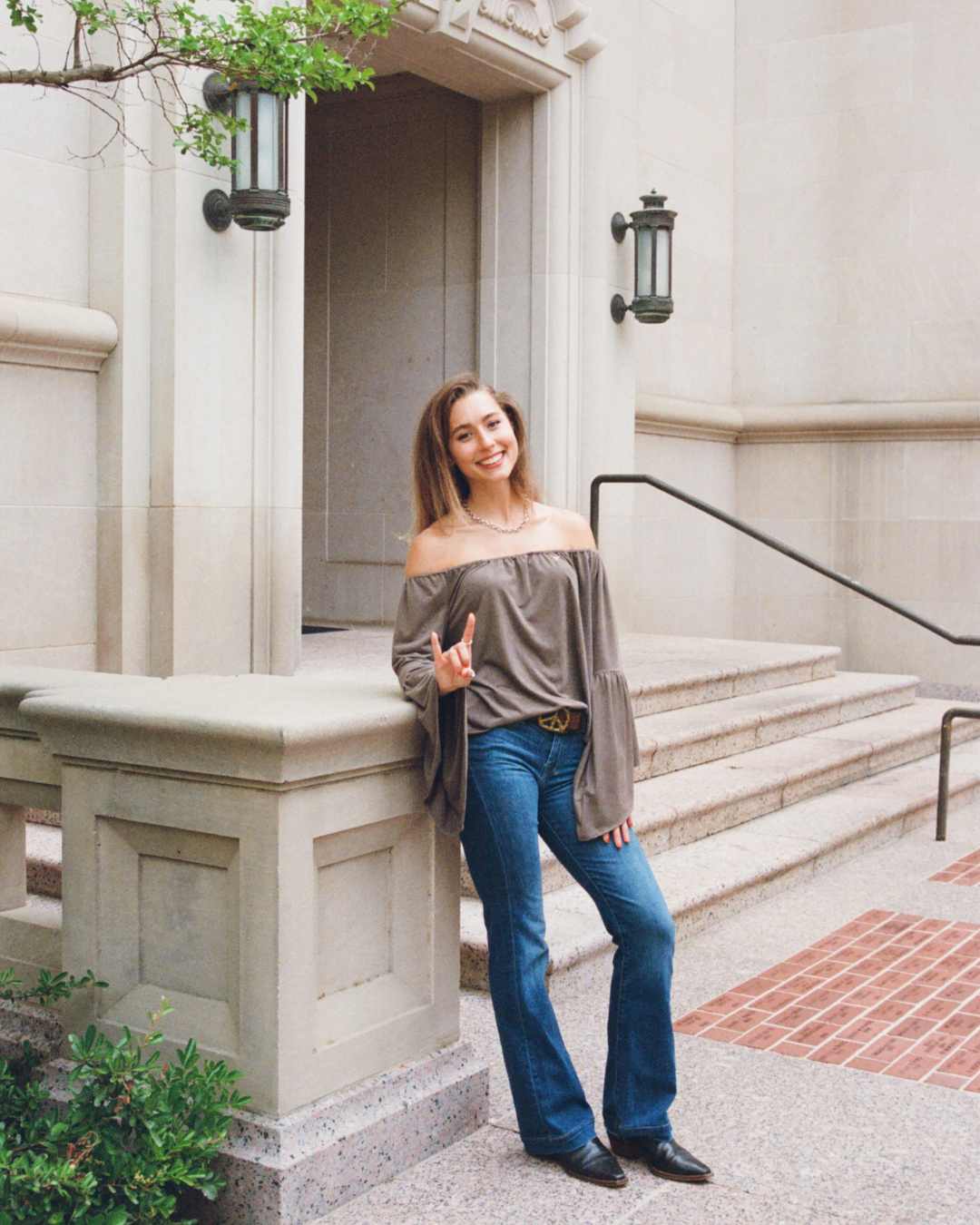 image of a woman leaning against a building holding up hook 'em