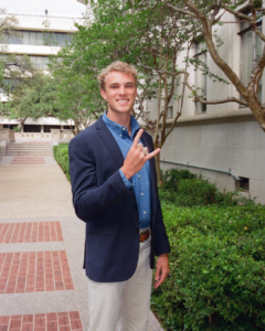 image of a man holding up a reverse hook 'em to show his conference ring