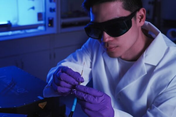 researcher wearing glasses and purple gloves hold probe