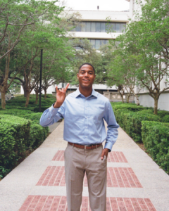 image of a man standing in the middle of a walkway holding up hook 'em