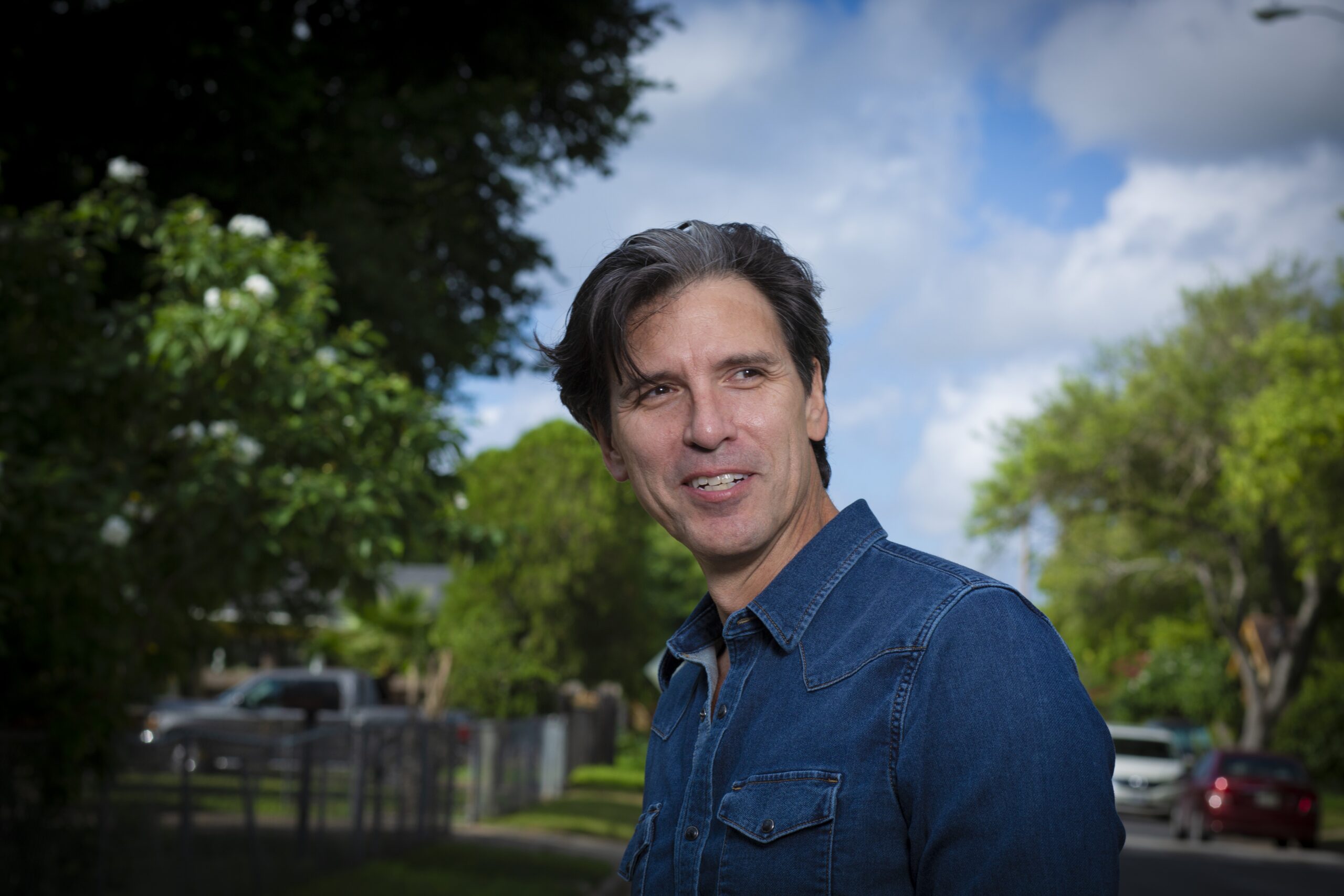 headshot of man outdoors wearing blue shirt