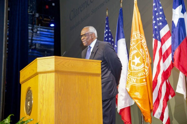 Justice Thomas stands at podium with flags in background