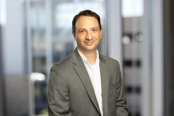 headshot of man wearing grey blazer
