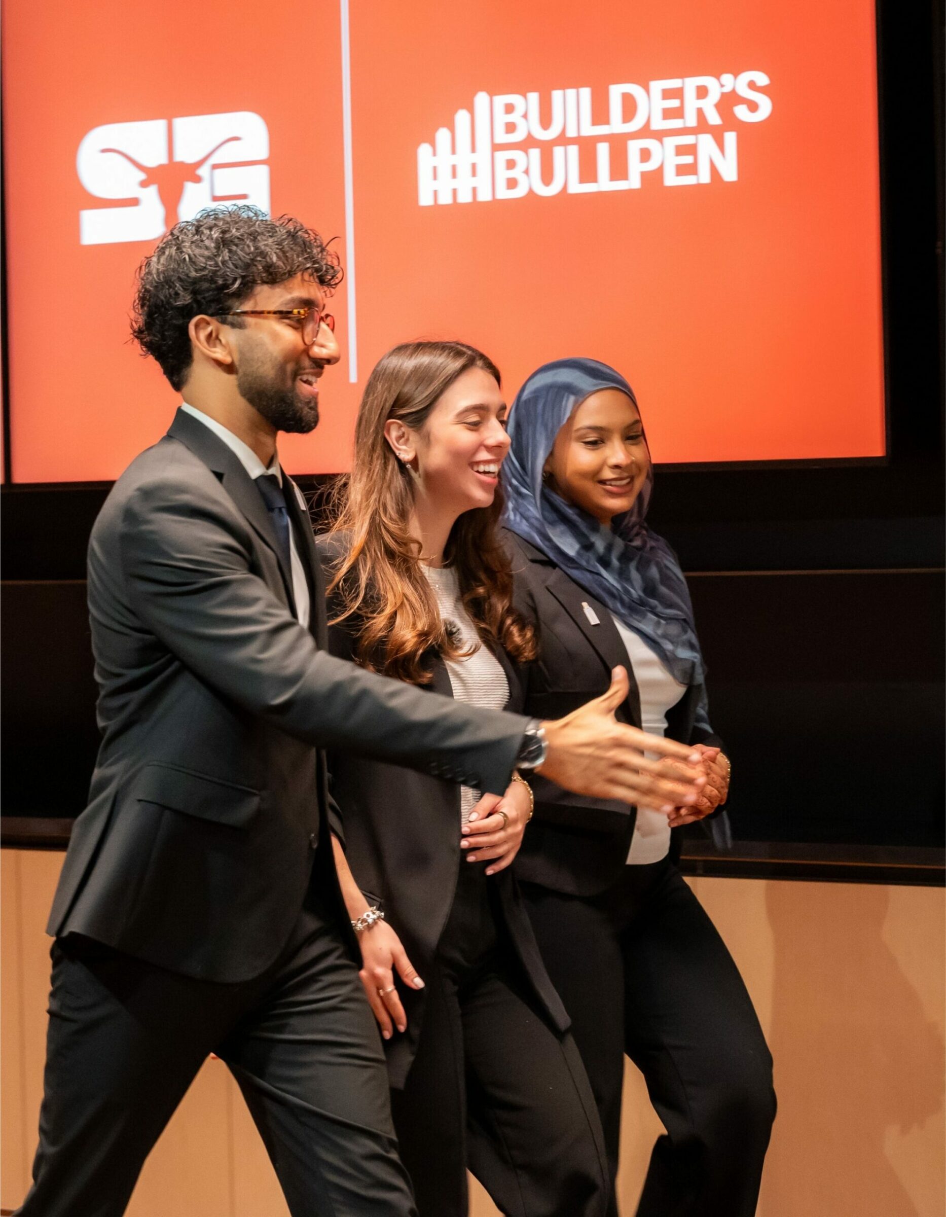 three students go up to accept their award at the Builder's Bullpen